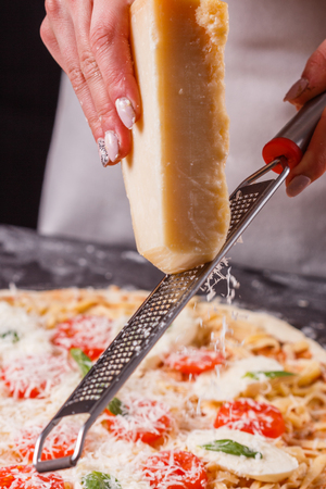 young woman in a gray aprong prepares a pizza margarita.の写真素材