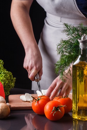 young woman slicing cheese in a gray apron.の写真素材
