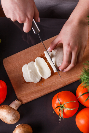 young woman slicing cheese in a gray apron.の写真素材