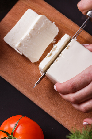 young woman slicing cheese in a gray apron.の写真素材
