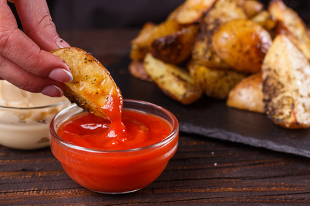 young woman dip fried potatoes to tomato sauce.の写真素材