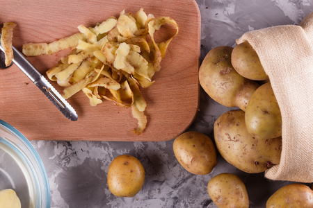 A young woman in an apron peeling potatoes.の写真素材