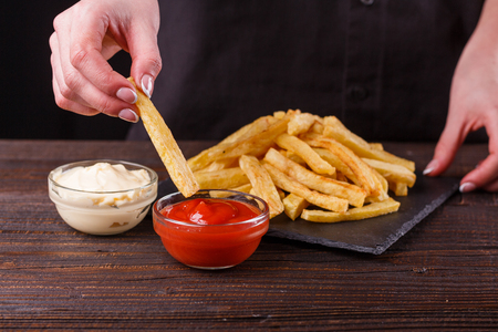 young woman dip french fries to tomato sauce.の写真素材
