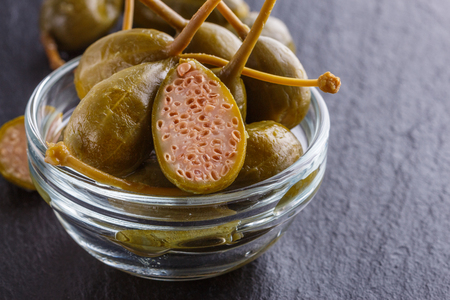 pickled capers on a dark stone background.の写真素材