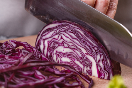 a young woman in a gray apron cuts red cabbage.