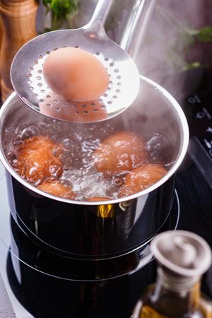 young woman in an gray apron boiled eggs.の写真素材