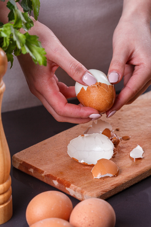 young woman in a gray apron cleans the boiled egg.