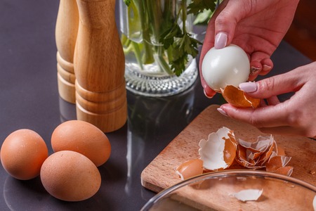 young woman in a gray apron cleans the boiled egg.の写真素材