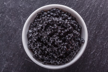 black caviar in a bowl on a dark stone background.の写真素材