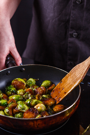 young woman fries Brussels sprouts on a frying pan.の写真素材