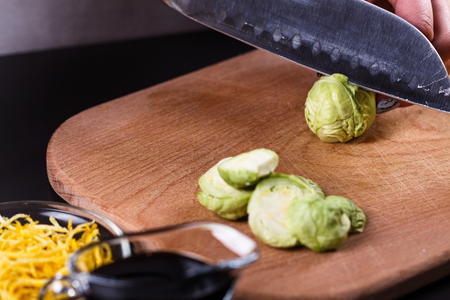 young woman cuts Brussels sprouts on a wooden cutting board.の写真素材