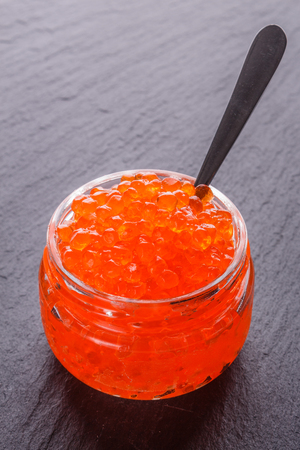 red caviar in a bowl on a dark stone background.の写真素材