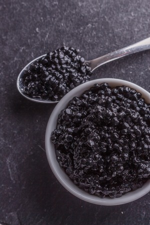 black caviar in a bowl on a dark stone background.の写真素材