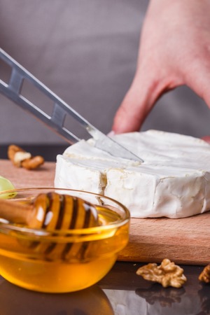young woman slicing cheese in a gray apron.の写真素材