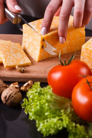 young woman slicing cheese in a gray apron.の写真素材