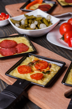 young woman is preparing a traditional Swiss cheese raclette.の写真素材