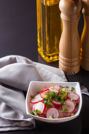Radish salad in a white bowl on a dark background.の写真素材