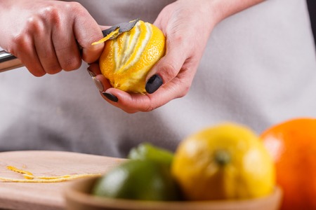 young woman in a gray aprons cuts lemon zest.の写真素材