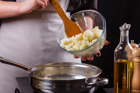 young woman in a gray apron roasts cauliflower broccoli.の写真素材
