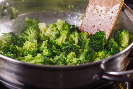young woman in a gray apron roasts cauliflower broccoli.の写真素材