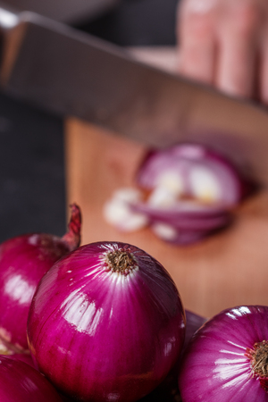 young woman in a gray aprons cuts red onion.の写真素材