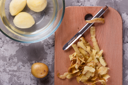 A young woman in an apron peeling potatoes.の写真素材