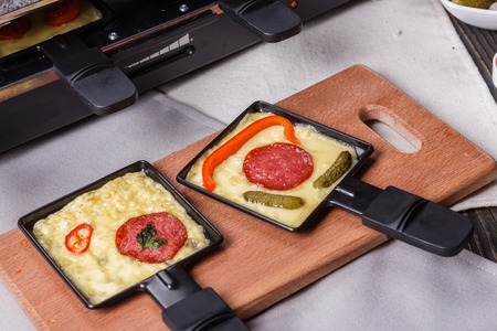 young woman is preparing a traditional Swiss cheese raclette.の写真素材