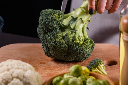 young woman in a gray aprons cuts cauliflower broccoli.の写真素材