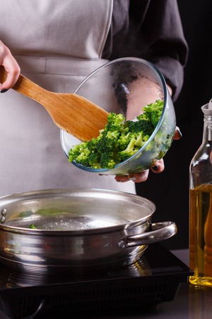 young woman in a gray apron roasts cauliflower broccoli.の写真素材
