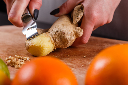 young woman in a gray apron peeling a ginger root.の写真素材