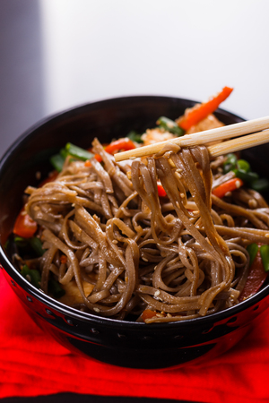Buckwheat noodle in a black bowl on chicken fillet.の写真素材
