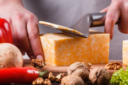 young woman slicing cheeseの写真素材