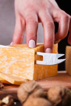 young woman slicing cheese in a gray apron.の写真素材