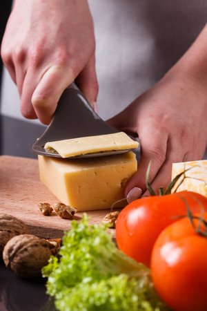 young woman slicing cheeseの写真素材