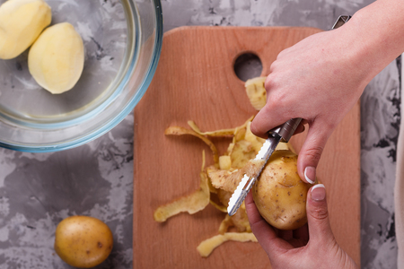 Top view of young woman peeling potatoesの写真素材