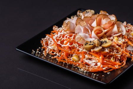 Salad with ham on black square plate.の写真素材