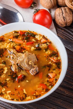 Georgian soup. Kharcho with rice, tomato, beef, garlic and herbs in bowl on wooden table.の写真素材