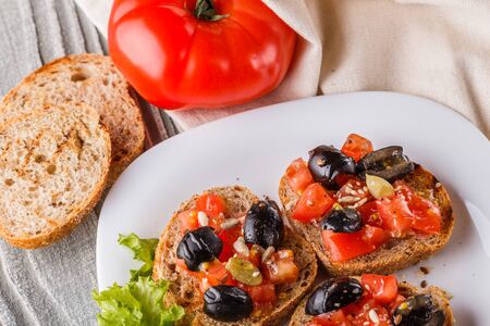 Italian bruschetta with tomato, black olives, lettuce and mustard.の写真素材
