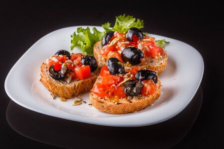 Italian bruschetta with tomato, black olives, lettuce and mustard.の写真素材