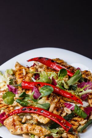 Mexican salad with hot pepper chiken fillet lettuce and nut on plateの写真素材
