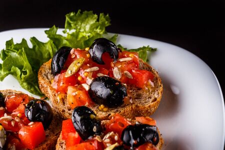 Italian bruschetta with tomato, black olives, lettuce and mustard.の写真素材