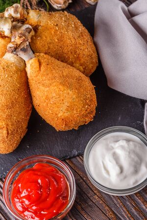 fried chicken leg in batter, red and white sauce on a dark surface.の写真素材