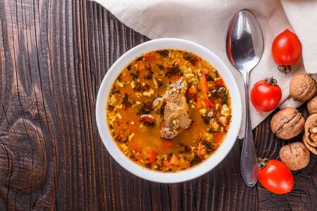 Georgian soup. Kharcho with rice, tomato, beef, garlic and herbs in bowl on wooden table.の写真素材