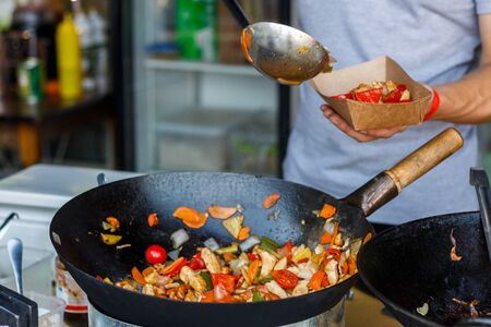 chef cooks vegetables at street food festival.の写真素材
