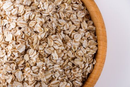raw oat flakes on white acrylic background.