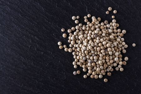 white peppercorns on dark slate stone background.の写真素材