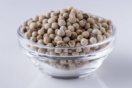 white peppers in glass bowl on white background.