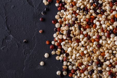 mix of quinoa grains on a dark stone background.