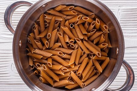 traditional italian pasta in a metal pan on a wooden background.の写真素材
