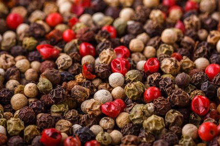 mix of peppercorns on white acrylic background.